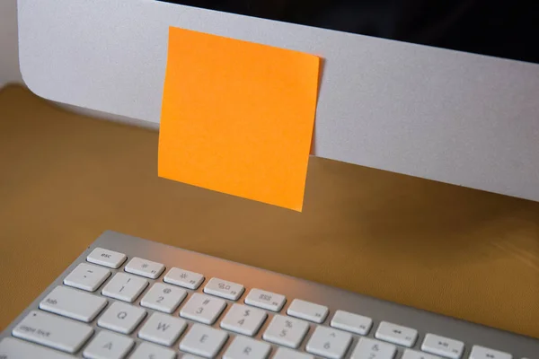 Ofisteki bilgisayardaki boş turuncu yapışkan nota yakın çekim 