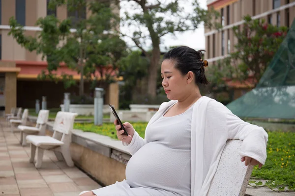 Parkta akıllı telefon kullanan Asyalı Hamile Kadın