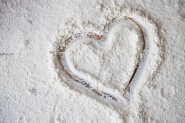 Bir çocuk tarafından boyalı ahşap masa üzerine un kalbinde