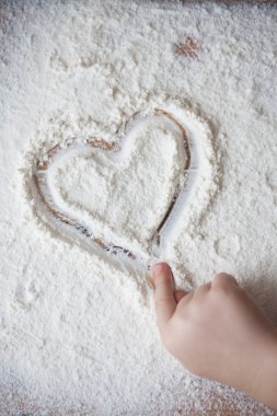 Bir çocuk tarafından boyalı ahşap masa üzerine un kalbinde