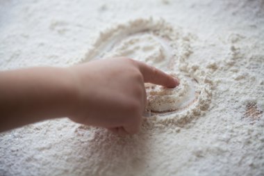 Bir çocuk tarafından boyalı ahşap masa üzerine un kalbinde