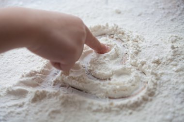 Bir çocuk tarafından boyalı ahşap masa üzerine un kalbinde