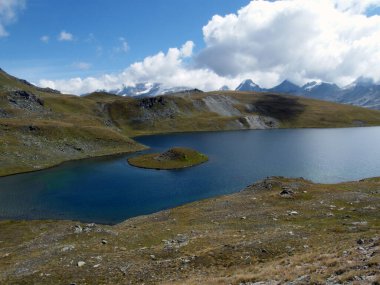 Ağustosta güneşli bir günde 2700 metre yüksekliğinde dağ zirveleri olan küçük bir dağlık göl manzarası.