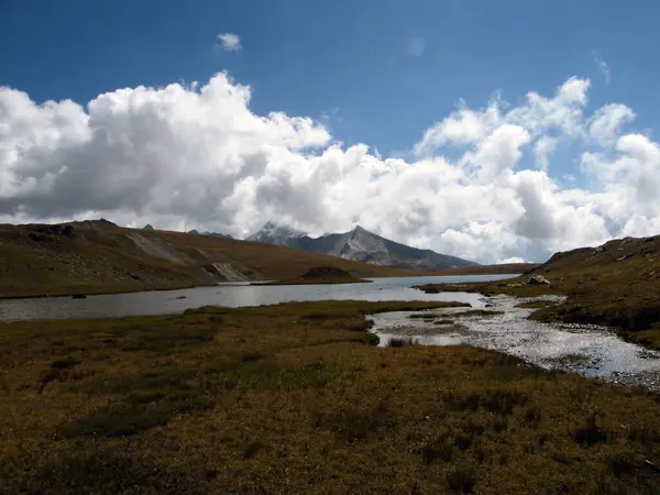 Ağustosta güneşli bir günde 2700 metre yüksekliğinde dağ zirveleri olan küçük bir dağlık göl manzarası.