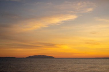 Günbatımı için portakal boyalı bir gökyüzü. Arka planda Elba adası profili var. Bir Şubat akşamı.