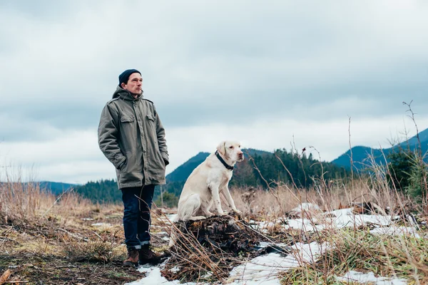 Homem e cão labrador caminhando nas montanhas — Fotografia de Stock