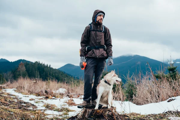 Caminhante com cão husky siberiano olhando para a bela vista nas montanhas — Fotografia de Stock