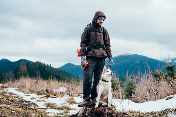 Caminhante com cão husky siberiano olhando para a bela vista nas montanhas — Fotografia de Stock