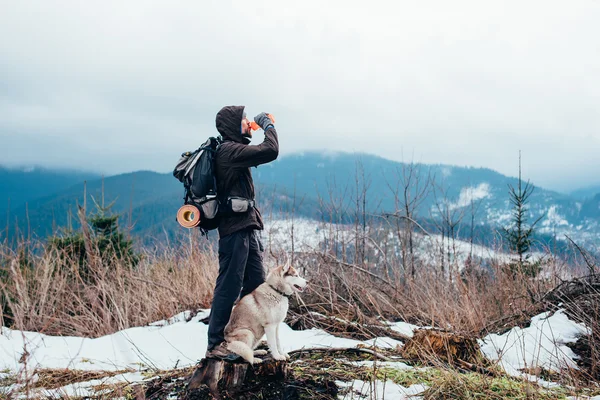 Caminhante com cão husky siberiano olhando para a bela vista nas montanhas — Fotografia de Stock