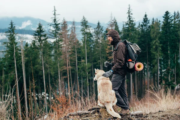 Caminhante com cão husky siberiano olhando para a bela vista nas montanhas — Fotografia de Stock