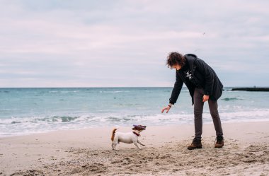 Kumsalda köpekle oynamayı adam