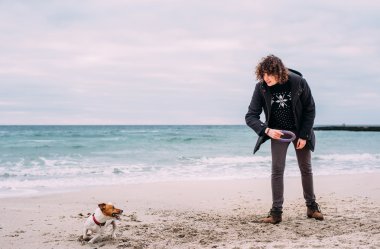 Kumsalda köpekle oynamayı adam