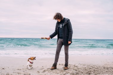 Kumsalda köpekle oynamayı adam