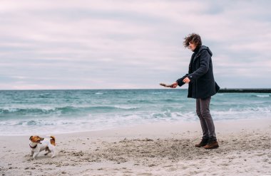 Kumsalda köpekle oynamayı adam