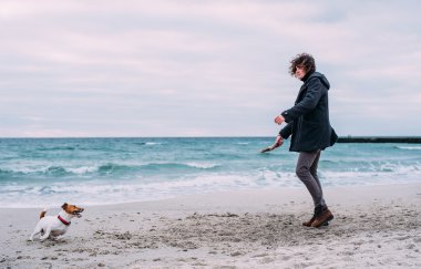 Kumsalda köpekle oynamayı adam