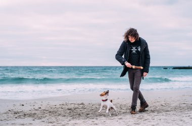 Kumsalda köpekle oynamayı adam