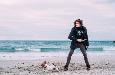 Kumsalda köpekle oynamayı adam