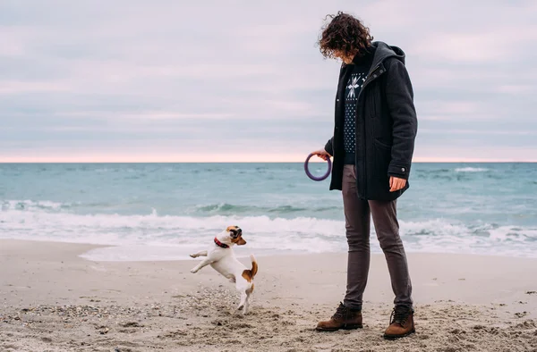 Hombre jugando con jack russel terrier en la playa — Foto de Stock