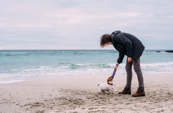 Man leker med hunden på stranden — Stockfoto