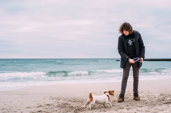 Man leker med hunden på stranden — Stockfoto