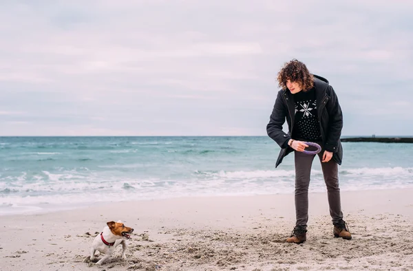 Kumsalda köpekle oynamayı adam