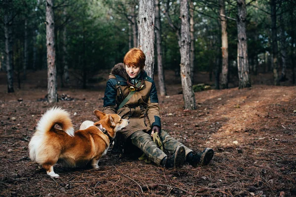 Rude dziewczyny spaceru z psem walijski corgi w lesie — Zdjęcie stockowe