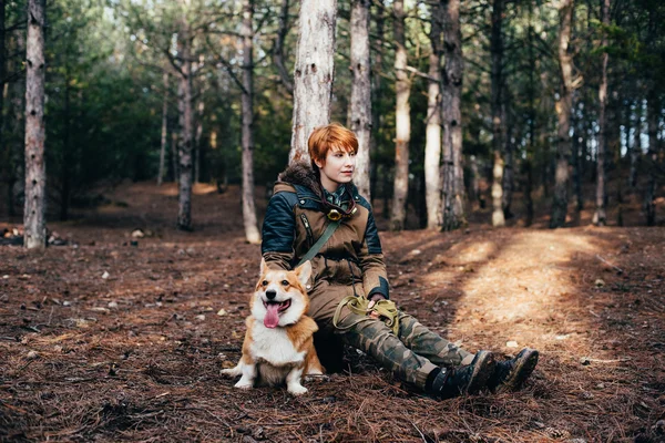 Rödhårig tjej med Walesiska corgi hund i skogen — Stockfoto