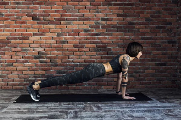 Τατουάζ γυναικείο κάνει ασκήσεις σε εσωτερικούς χώρους, σπορ γυναίκα την πρακτική της γιόγκα — Φωτογραφία Αρχείου