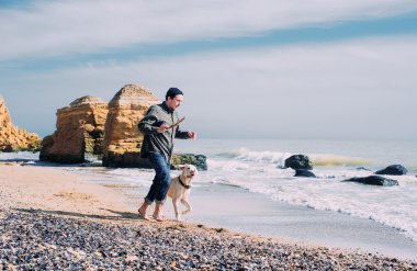 Labrador köpek ile kumsalda oynarken adam