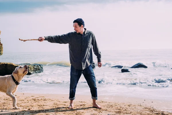Мужчина играет с собакой-лабрадором на пляже — стоковое фото
