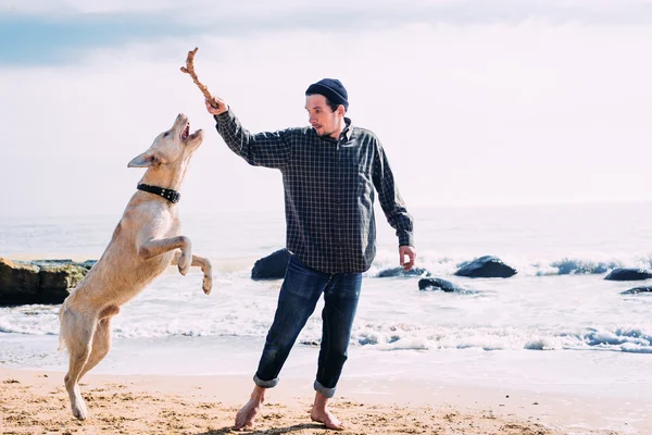 Ο άνθρωπος παίζει με σκύλος labrador στην παραλία — Φωτογραφία Αρχείου