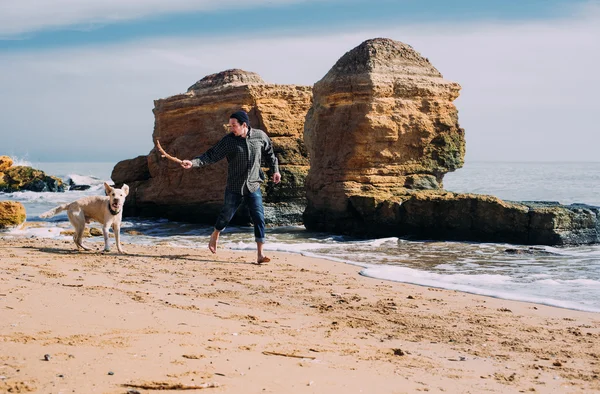 Labrador köpek ile kumsalda oynarken adam — Stok fotoğraf