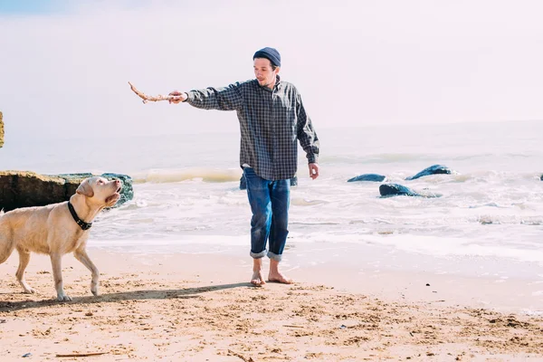 Ο άνθρωπος παίζει με σκύλος labrador στην παραλία — Φωτογραφία Αρχείου