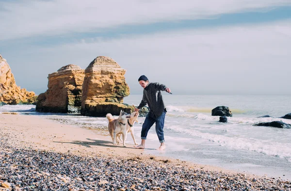 Mężczyznę idącego z siberian husky i labrador pies na plaży — Zdjęcie stockowe