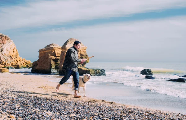 Чоловік грає з собакою-лабрадором на пляжі — стокове фото