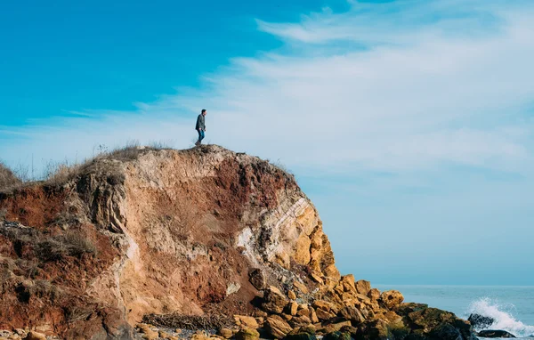 Hombre de pie en un acantilado y mirando al mar — Foto de Stock