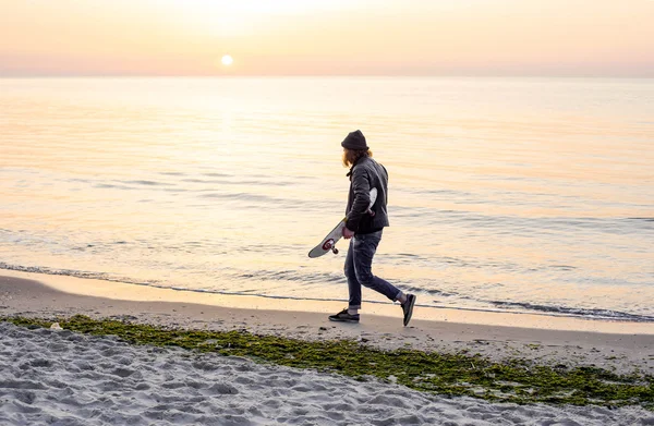 Homem com patins na praia durante o pôr do sol ao nascer do sol — Fotografia de Stock