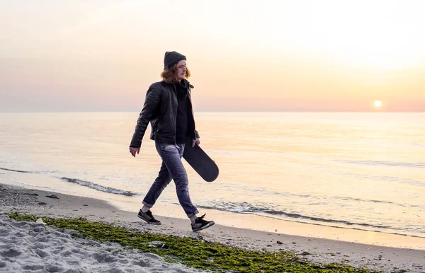 Homem com patins na praia durante o pôr do sol ao nascer do sol — Fotografia de Stock