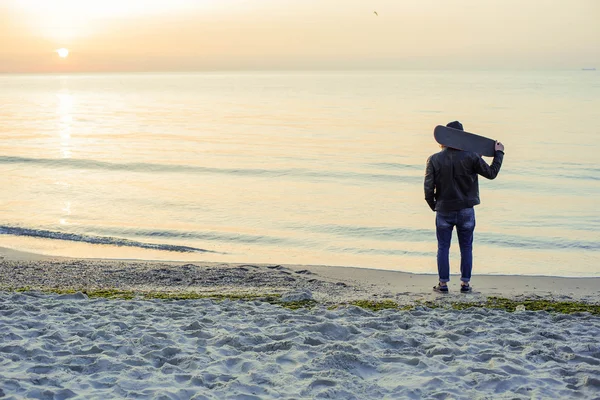 Hombre con patín en la playa al atardecer al amanecer —  Fotos de Stock