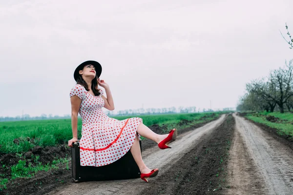 Mujer en ropa vintage con maleta en el campo . — Foto de Stock