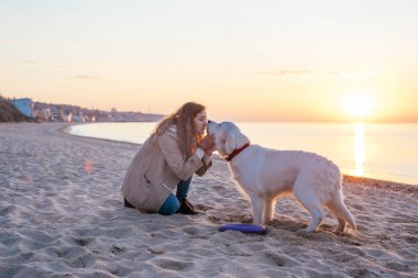 Genç bir kadın köpeğiyle oynuyor.