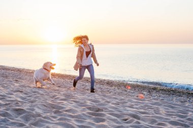 Genç bir kadın köpeğiyle oynuyor.