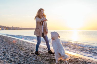 Genç bir kadın köpeğiyle oynuyor.