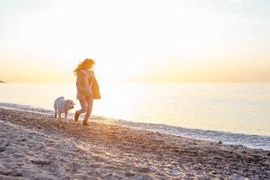 Genç bir kadın köpeğiyle oynuyor.