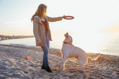Genç bir kadın köpeğiyle oynuyor.