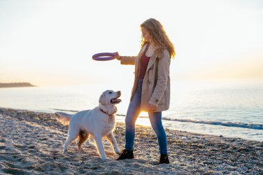 Genç bir kadın köpeğiyle oynuyor.