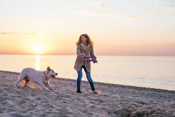 Genç bir kadın köpeğiyle oynuyor.