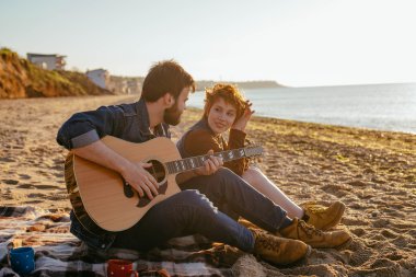 couple playing guitar on beach clipart
