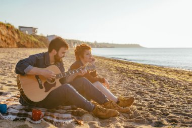 Çift sahilde gitar çalmak