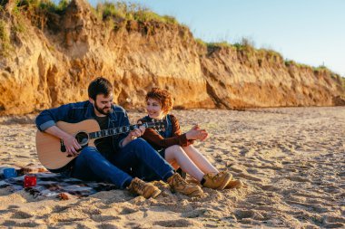 Çift sahilde gitar çalmak